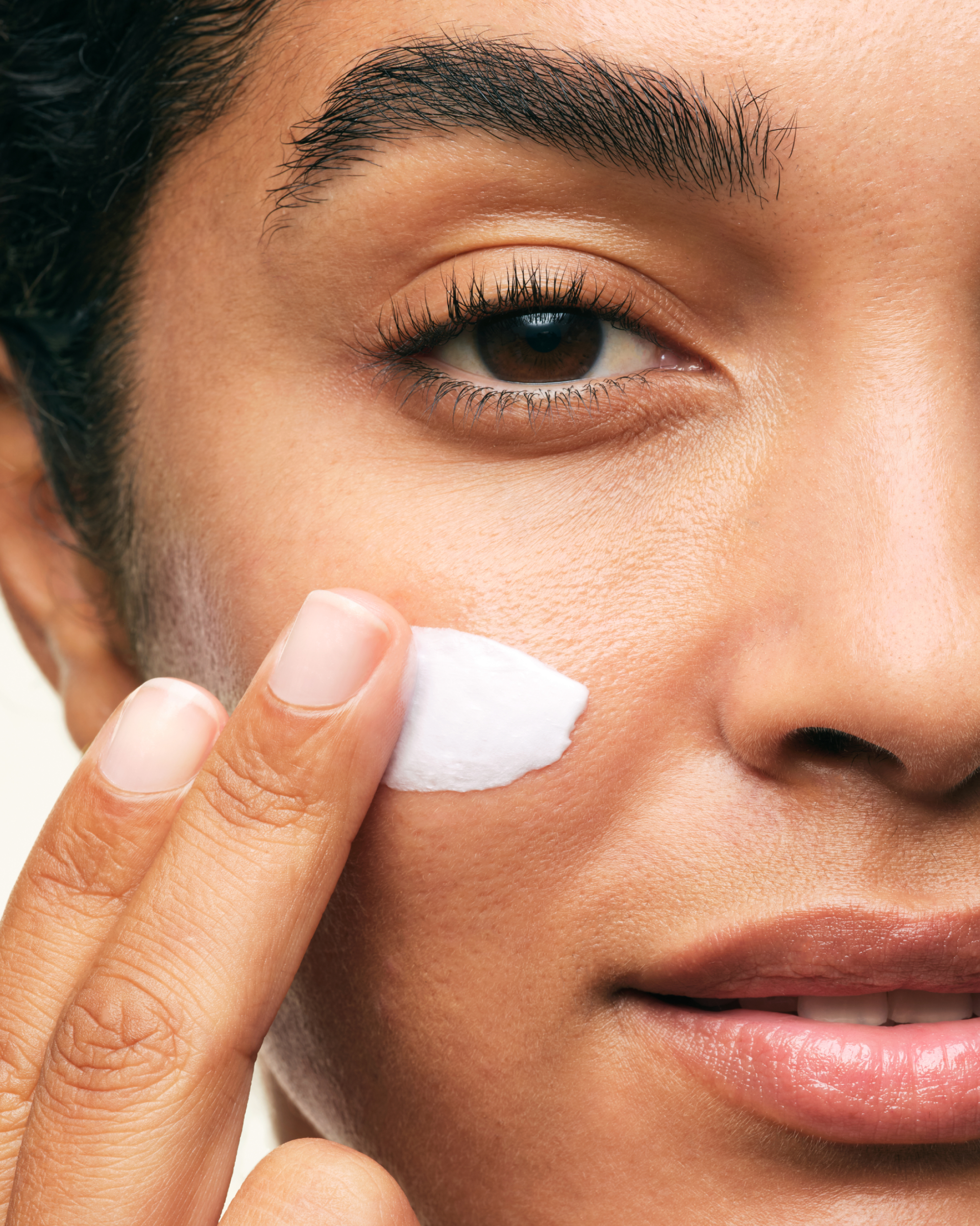 A person applying Skinfix Ceramide Prime Whipped Cream to their cheek.