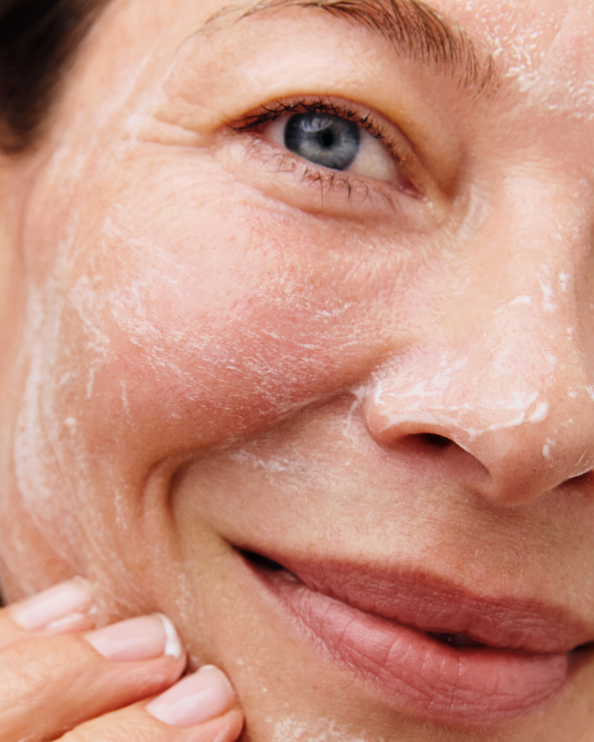 Close-up of a person cleansing their face, with a foaming cleanser visible on the skin.