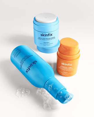 Skinfix Foaming Oil Cleanser bottle with bubbles, Triple Lipid-Peptide Cream jar, and Brighten + Firm 15% Vitamin C Serum displayed on a light background.