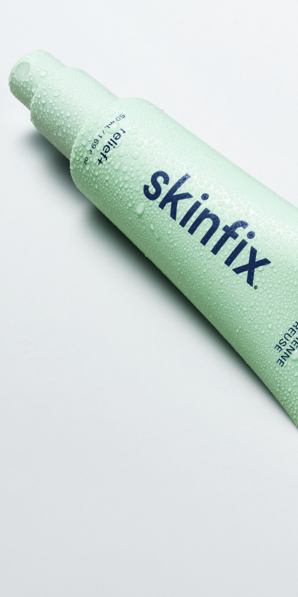 A light green tube Skinfix Hypochlorous Dailt Mist layong on white background, covered in water droplets.