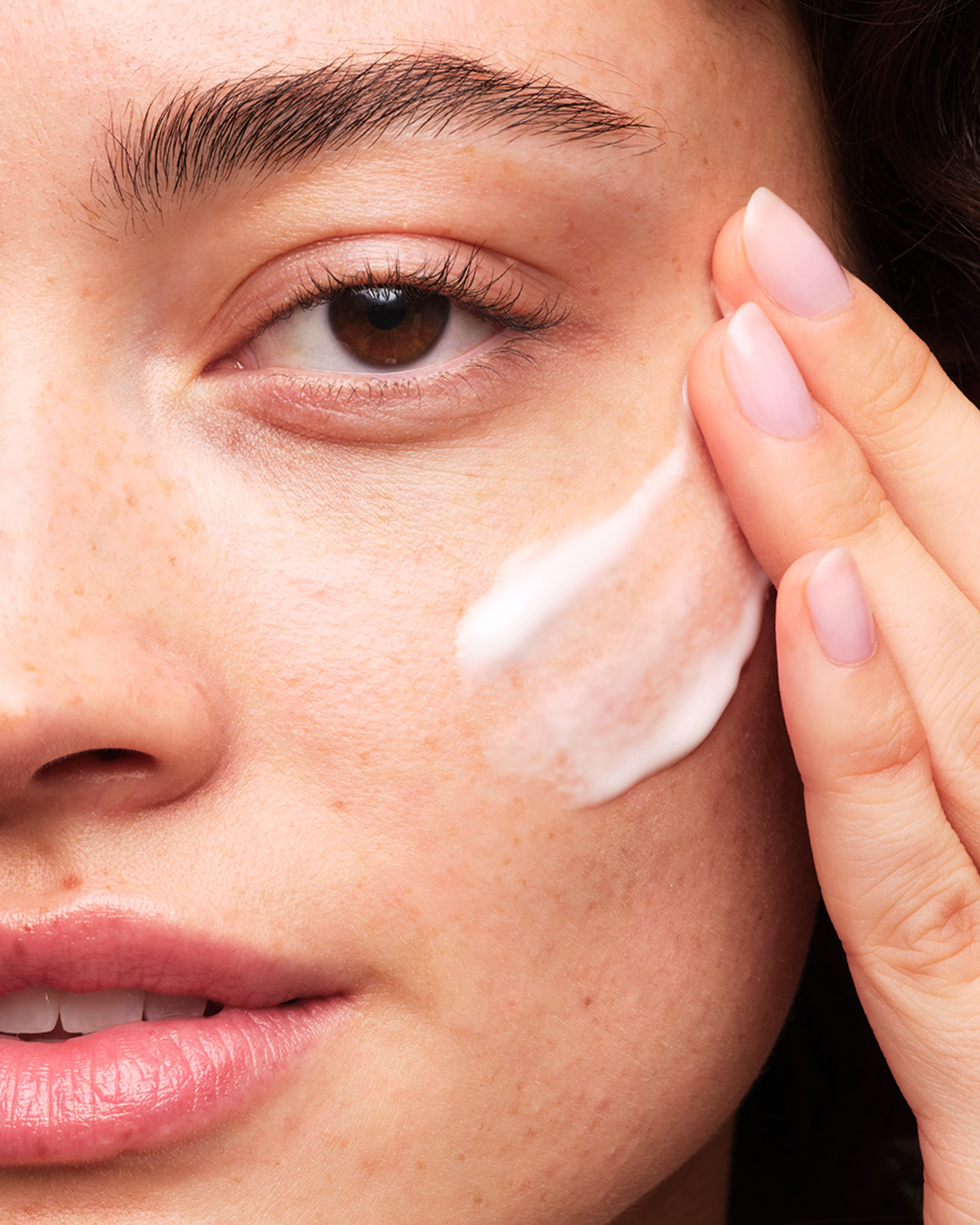 Person applying Skinfix Brighten + Firm 15% Vitamin C to their cheek.