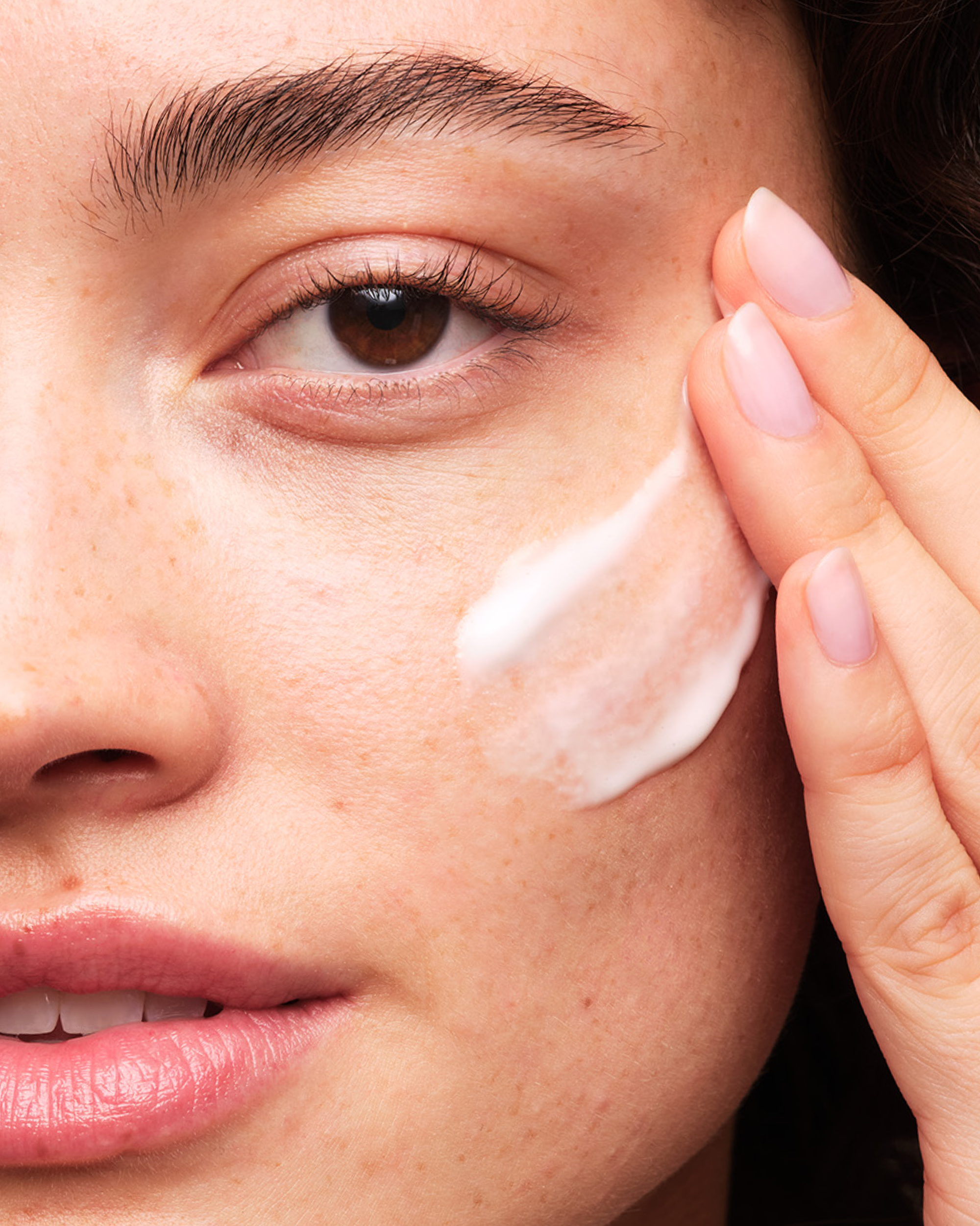 Person applying Skinfix Brighten + Firm 15% Vitamin C to their cheek.