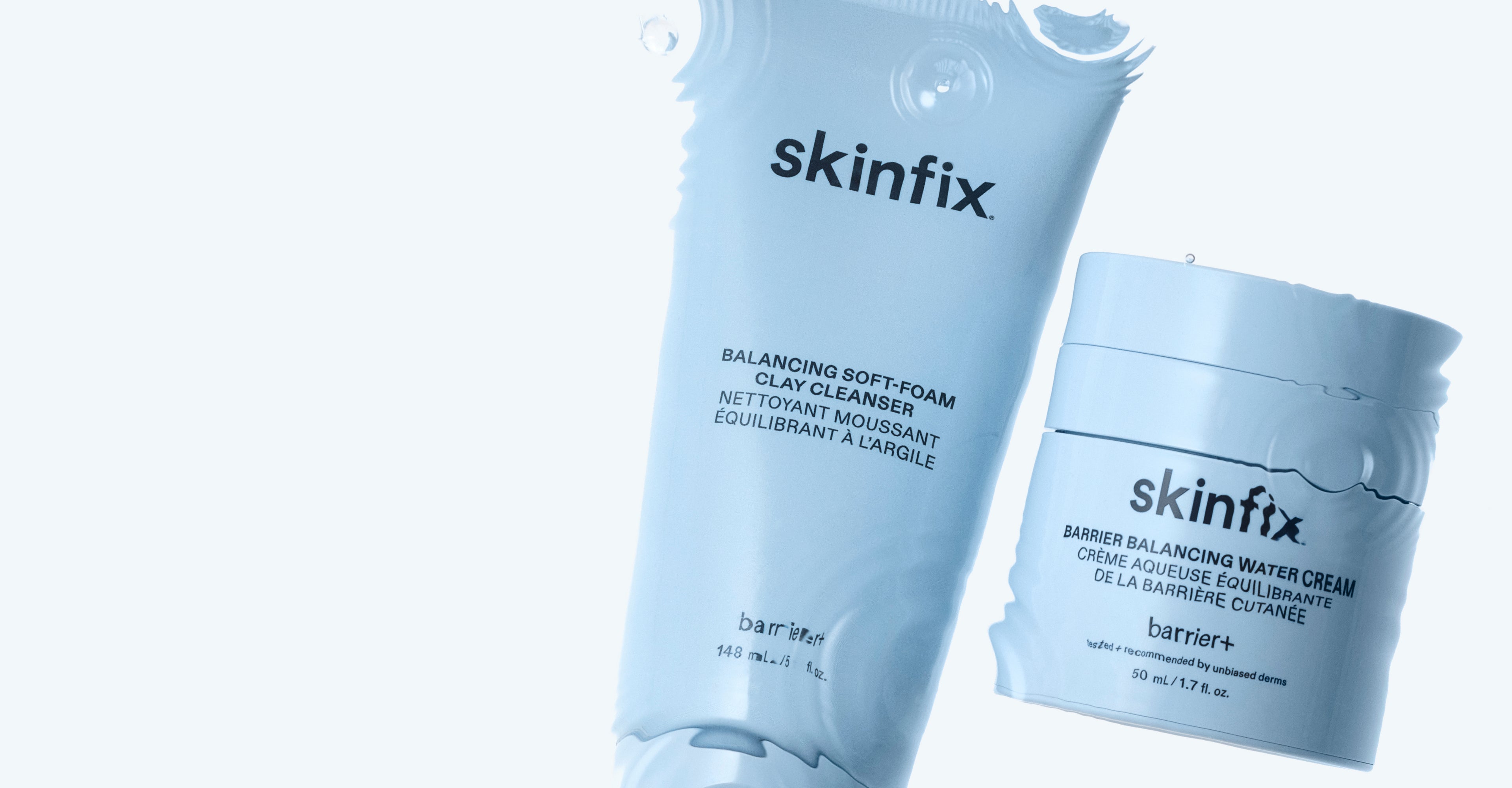 Skinfix Balancing Soft-Foam Clay Cleanser and Barrier Balancing Water Cream in light blue packaging, surrounded by water droplets and splashes, on a light blue background.